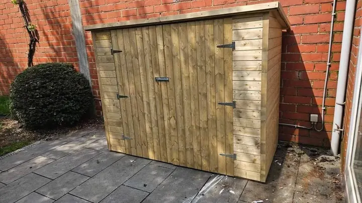 Houten tuinkast geplaatst tegen een buitenmuur