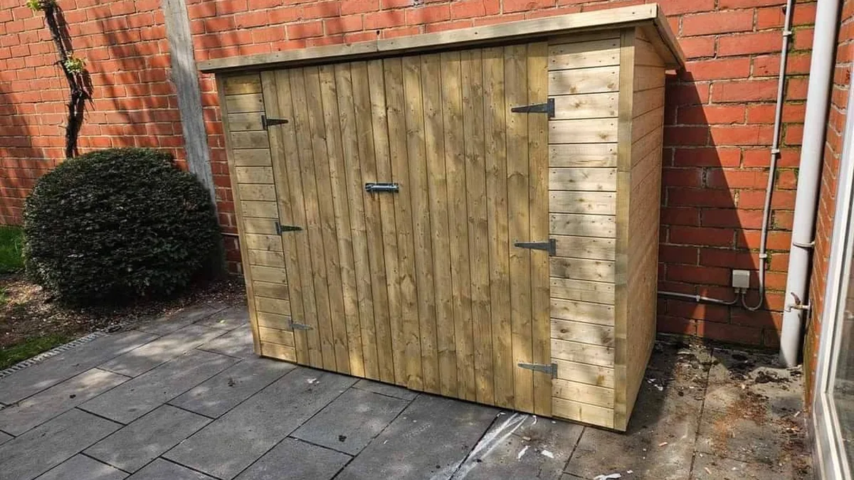 Houten tuinkast geplaatst tegen een buitenmuur